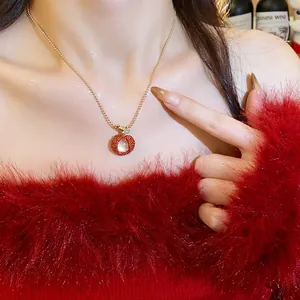 Detail shot of a red lychee-shaped resin pendant necklace worn with a fuzzy red sweater