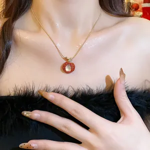 Close-up view of a delicate red lychee pendant necklace worn on a elegant female neck.