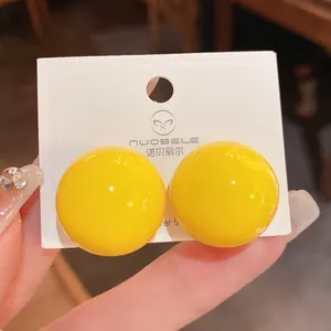 Primo piano di orecchini a lobo a sfera giallo brillante lucido con aghi in argento S925