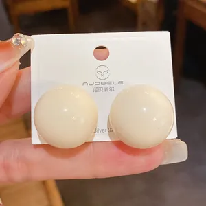 Dettaglio ravvicinato di orecchini a perno sferici color crema con perni in argento