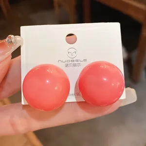 Dettaglio di grandi orecchini a lobo a sfera rosa corallo lucido con perni in argento S925.