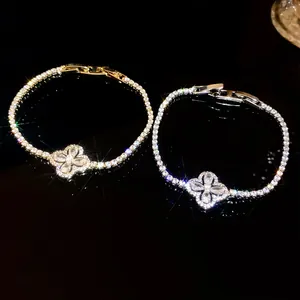 Close-up of gold and silver plated bracelets with sparkling four-petal flower zircon motifs.