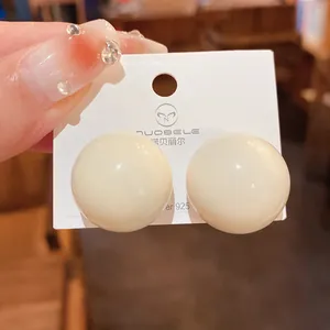 Dettaglio ravvicinato di grandi orecchini a sfera bianco crema con perni in argento 925
