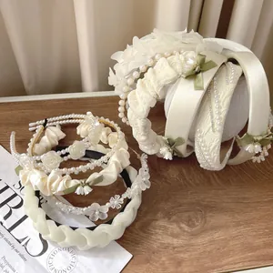 Eleganti cerchietti crema con fiori e perle e delicati dettagli in nastro a mughetto.