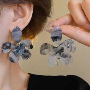 Close-up detail of blue marble resin flower earrings featuring a delicate ink-wash texture