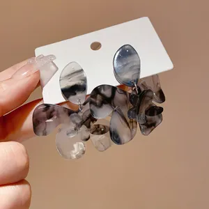 Detailed close-up of grey marble resin flower drop earrings on white display card