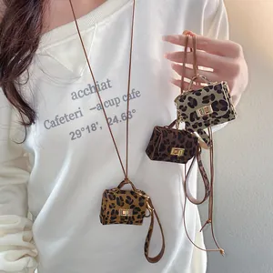 Detail of leopard print leather mini bag pendants on a stylish necklace worn by model