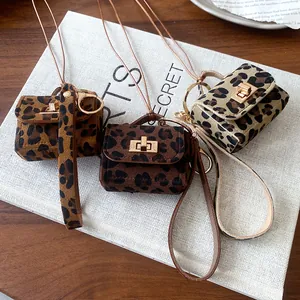 Set of three leopard-print miniature bag necklaces displayed on a white book prop.