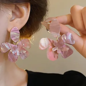Elegant large resin flower earrings featuring pink marbled ink pattern shown on model