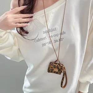 Close-up view of a stylish leopard print mini bag pendant necklace on a white sweatshirt
