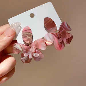 Macro view of marbled resin flower earrings with delicate petals on a white display card