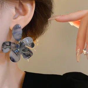 Detailed macro view of a blue resin flower earring with elegant marbled texture worn on ear