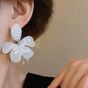 Macro view of marbled white resin flower earring with hypoallergenic silver needle