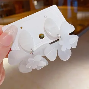 Close-up of white resin flower earrings with delicate marbled texture on display card