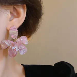Close-up of pink marbled flower resin earrings with silver needles on model's ear