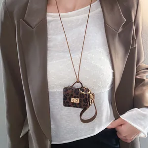 Detailed close-up view of a leopard print leather mini bag charm necklace on a model.