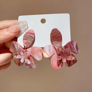 Close-up of pink marbled resin flower earrings with delicate layered floral petals