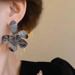 Detailed close-up of elegant dark marbled resin flower earrings worn by a model