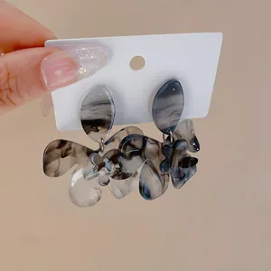 Close-up detail of ink-wash marble effect resin flower earrings with silver needle.