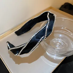 Dettaglio di un elegante cerchietto in tessuto nero decorato con catene di strass lucidi