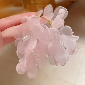 Primer plano de pendientes de flores de malla rosa con cuentas de cristal y aros