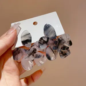 Close-up of elegant floral resin earrings with unique black ink-wash marble texture