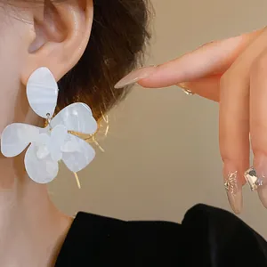 Elegant white resin flower earrings with marbled texture shown on a model's ear