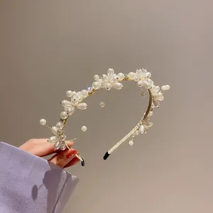 Dettaglio di un elegante cerchietto floreale con perle bianche e accenti dorati
