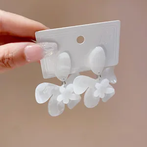 Close-up of white marbled resin flower earrings on a white jewelry display card