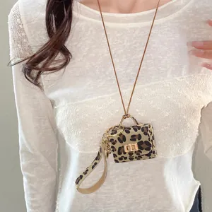 Detail of a chic leopard print leather mini bag pendant necklace worn on a white lace top