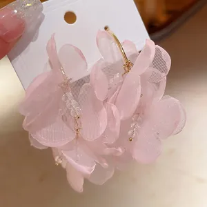 Primer plano detallado de los pétalos de malla rosa y las cuentas de cristal de estos pendientes de flores.