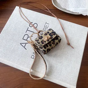 Detailed view of miniature leopard print bag charm with gold clasp and lanyard