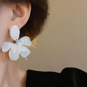 Close-up detail of white marbled resin flower earring worn by a model.