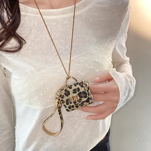 Detail view of miniature leopard print leather bag pendant necklace worn by model.