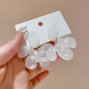 Detailed macro view of white resin flower earrings with marble ink dye effect.