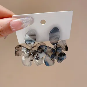 Close-up detail showing elegant gray floral resin earrings with marble ink pattern texture