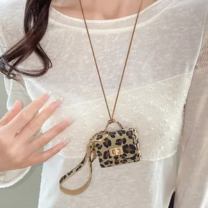 Close-up of leopard print leather mini bag pendant on a gold chain necklace.
