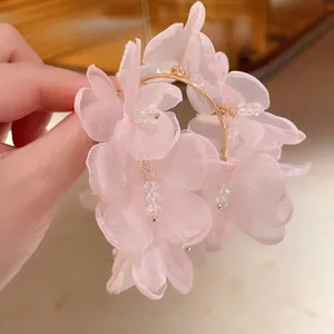 Vista detallada de pendientes de flores de malla rosa con cuentas de cristal y aro dorado.