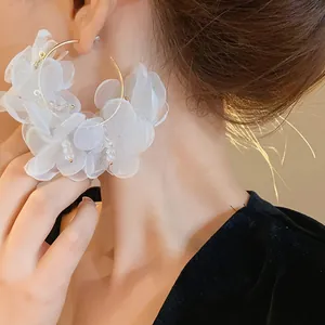 Primer plano detallado de pendientes de aro con flores de organza blanca y cristal
