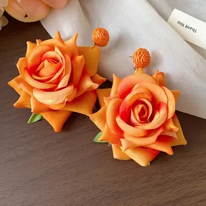 Elegantes pendientes de rosa de tela naranja con detalle de bola tejida en rafia