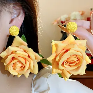Primer plano detallado de pendientes de rosa de tela amarilla con textura realista
