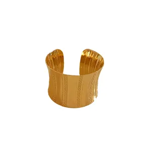 Elegant wide gold metal cuff bracelet with bold textured ridges and an open design