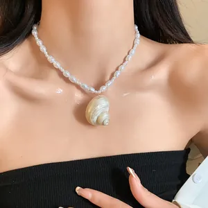 Primo piano di una collana di perle barocche con pendente a conchiglia su una modella.