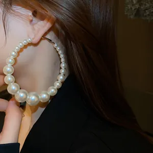 Detailansicht von eleganten, übergroßen weißen Perlenohrringen, die ein Model trägt