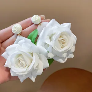 Primer plano de elegantes pendientes de rosa de tela blanca con pétalos románticos