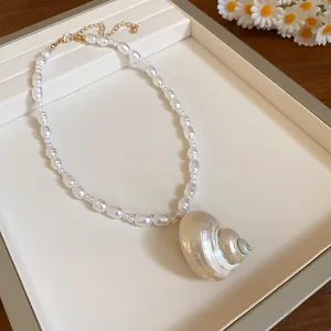 Vista dettagliata di una collana di perle barocche con un grande ciondolo a forma di conchiglia