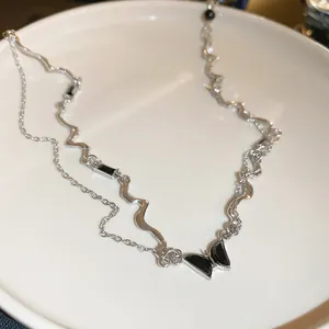 Detailed macro view of silver wavy chain and black enamel butterfly pendant jewelry
