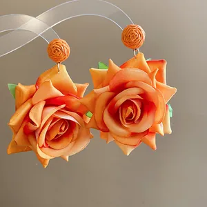Primer plano de elegantes pendientes de rosa de tela naranja hechos a mano