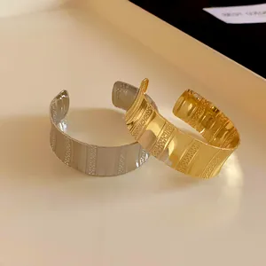 Close-up of stylish textured metal open cuff bangles in gold and silver finishes