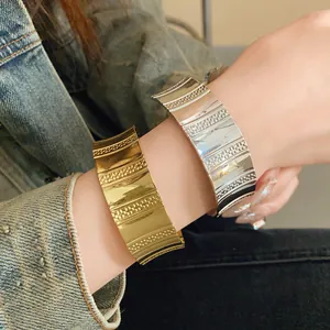 Detailed view of fashionable wide metallic open-cuff bracelets in gold and silver